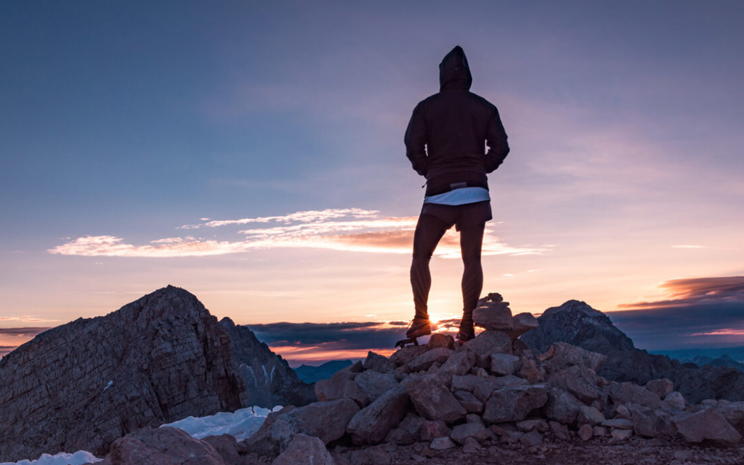 person standing on cliff at sunset